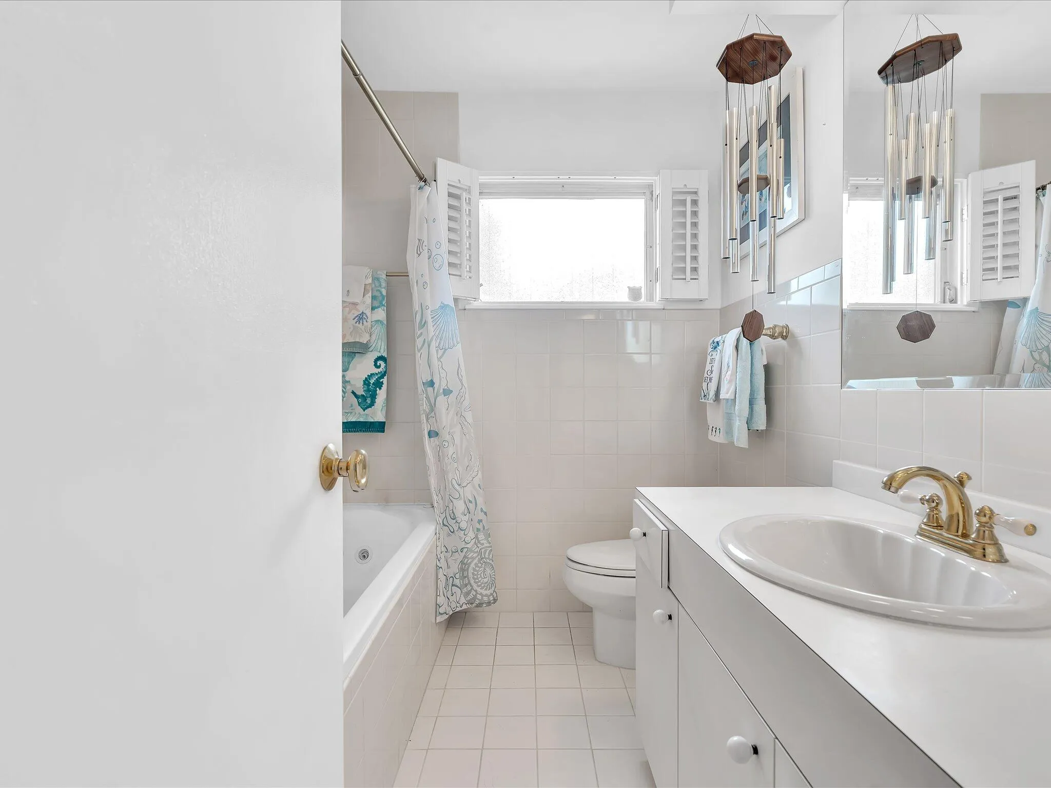 Full bathroom featuring a window, vanity with integrated sink, gold-tone faucet, and tiled shower/tub combination