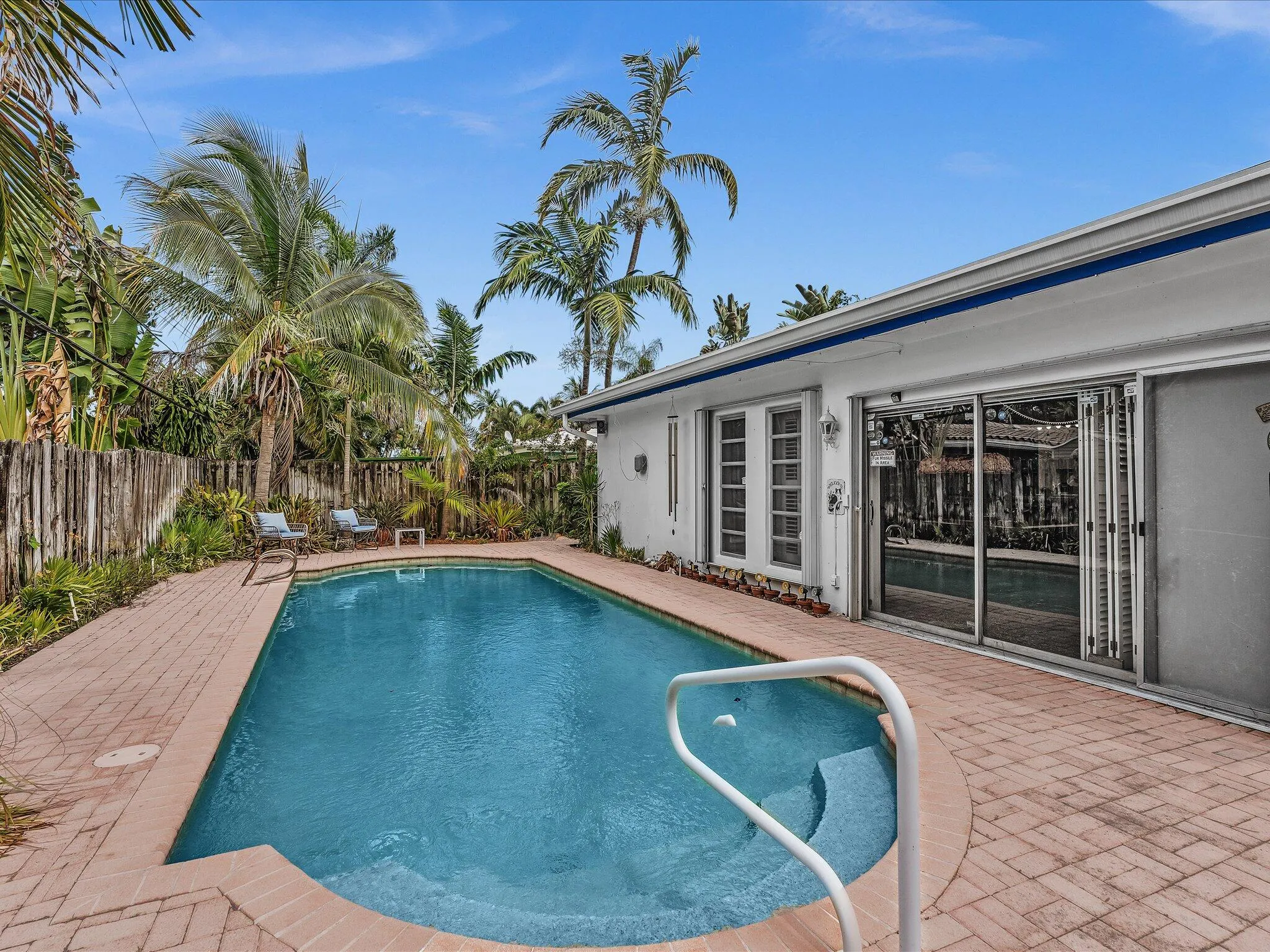 In-ground swimming pool with integrated steps, surrounded by brick paver decking
