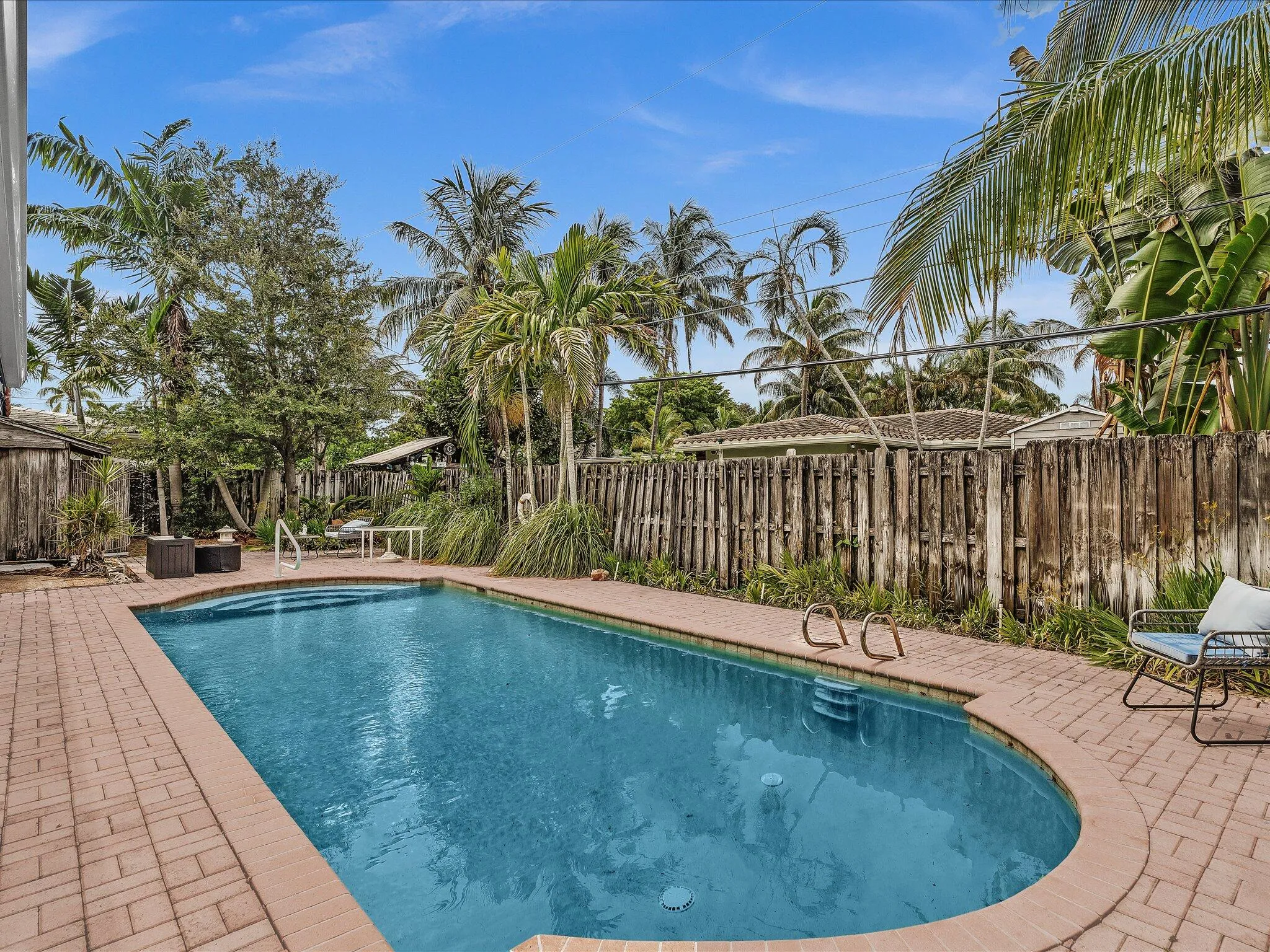 Rectangular swimming pool with integrated steps, surrounded by a brick paver deck