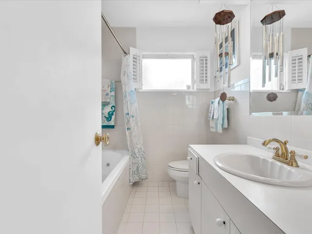 Full bathroom featuring a window, vanity with integrated sink, gold-tone faucet, and tiled shower/tub combination