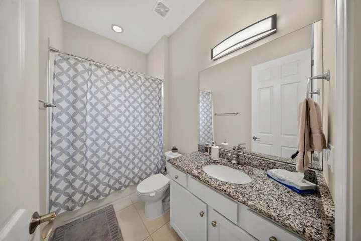 Bathroom featuring a single vanity with stone-finish countertop, undermount sink, and full-width wall mirror