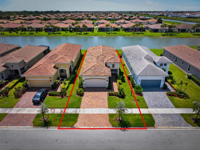 Waterfront property featuring a paver driveway, two-car garage, and established landscaping