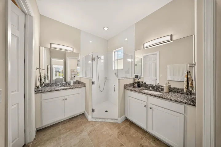 Primary bath features double vanities and sinks with a shower with glass door