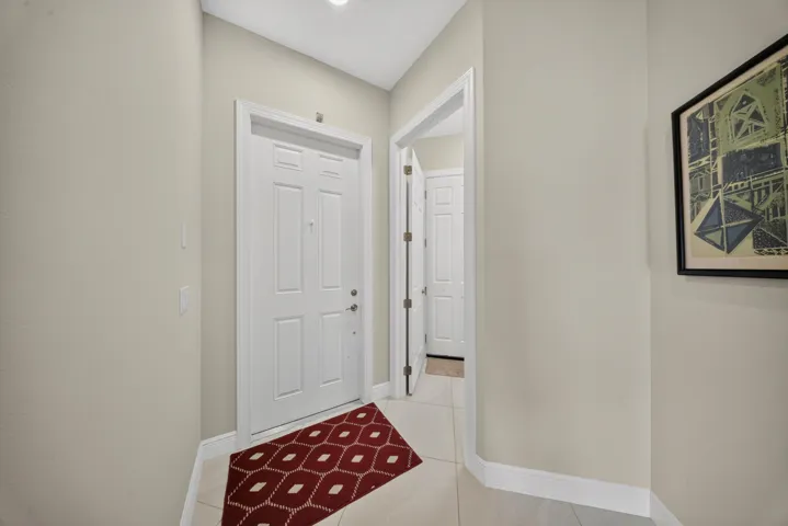Entryway featuring a white paneled door, light neutral wall tones, white baseboards, and light tile flooring