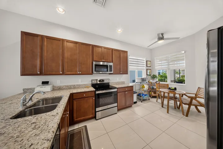 Kitchen featuring wood-finish cabinetry, granite countertops, stainless steel appliances, and large format tile flooring