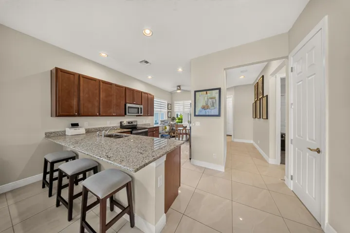 Kitchen with extensive cabinetry, a speckled countertop, integrated sink, recessed lighting, and tile flooring