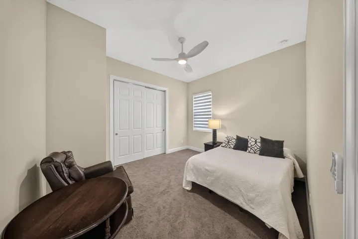 Carpeted room with a ceiling fan, window blinds, and paneled bifold closet doors