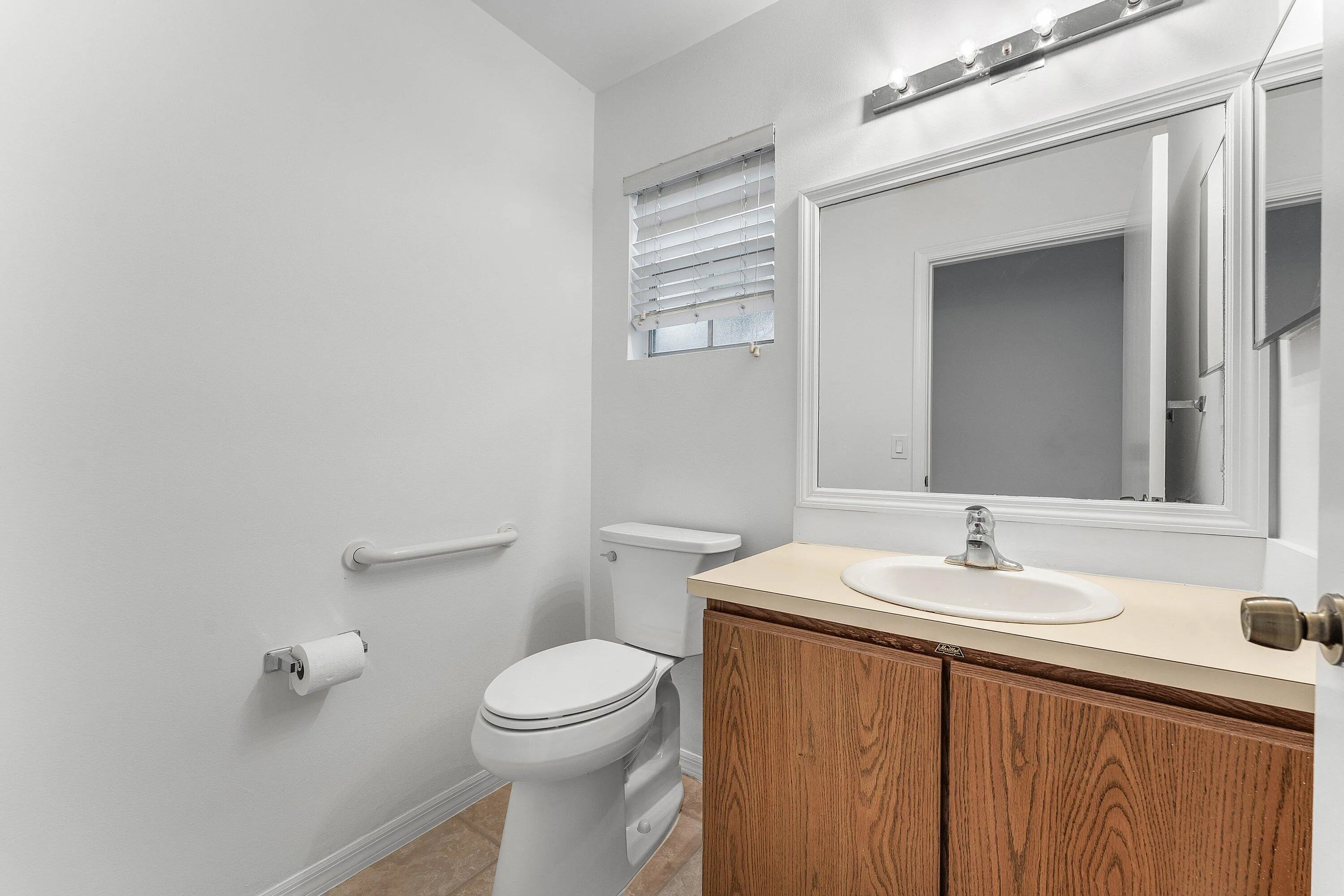 Bathroom featuring a wood-finish vanity with an integrated sink and light-toned countertop