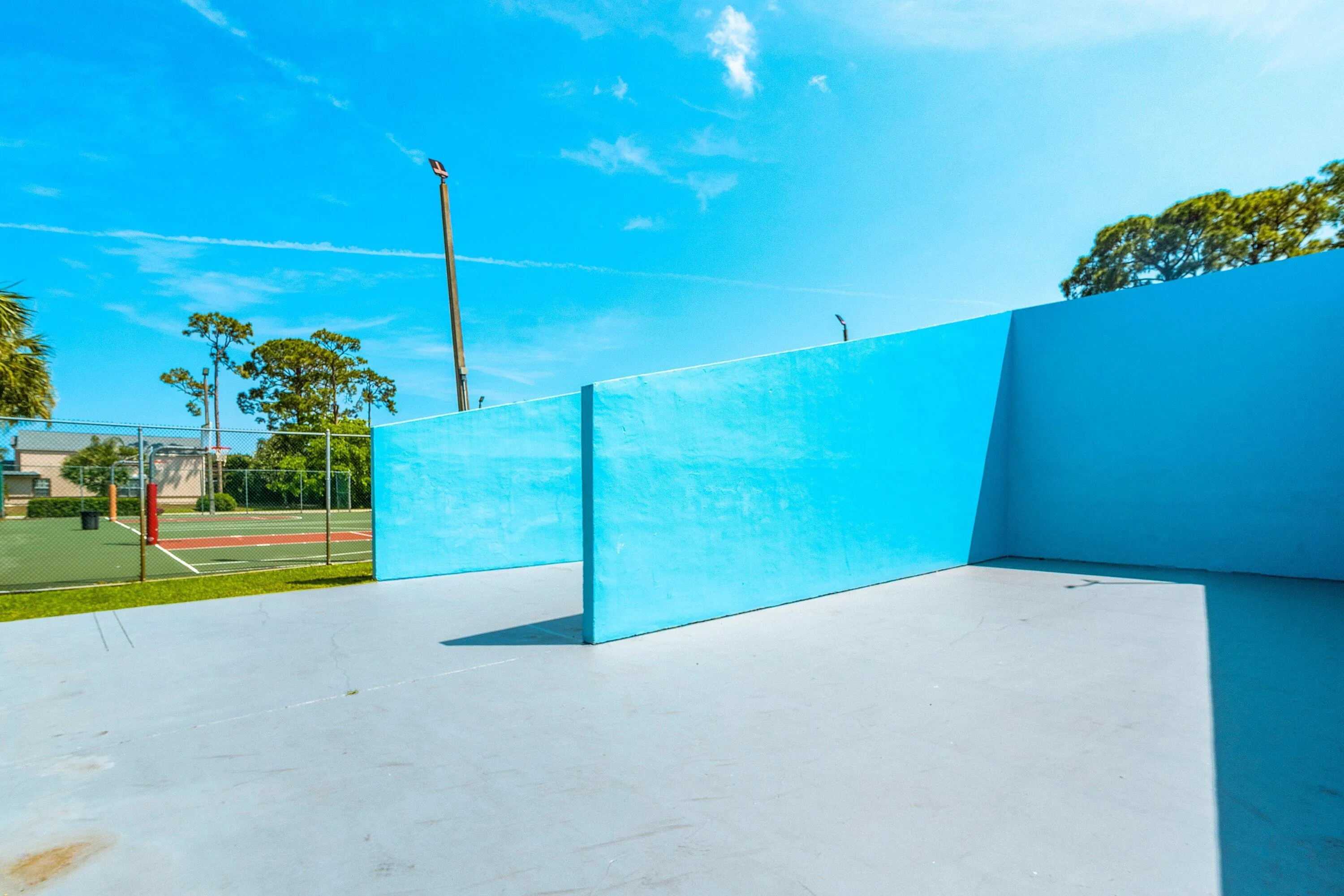 Outdoor recreational area featuring a light blue paved surface and vibrant blue walls