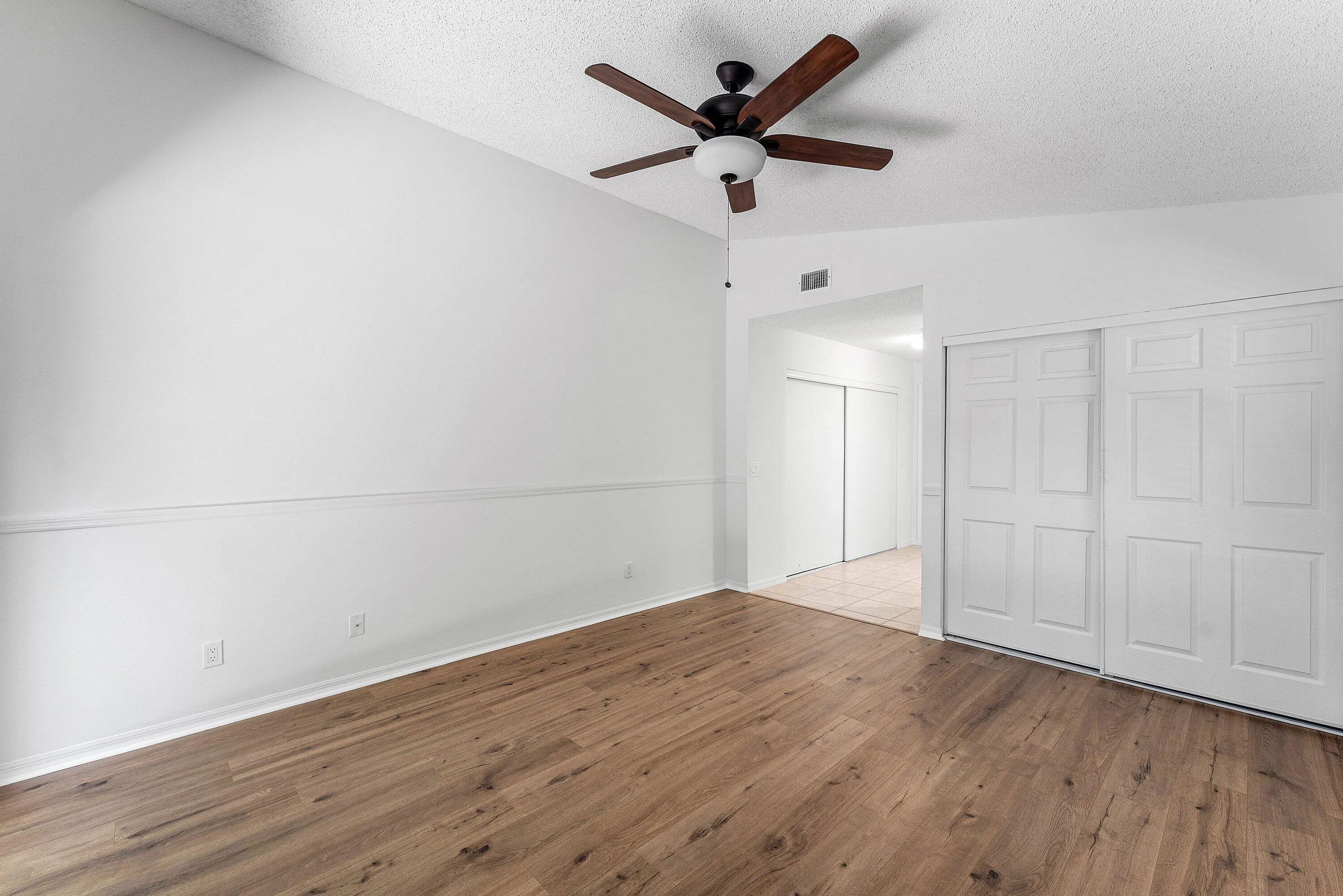 Room featuring wood-finish flooring, vaulted ceiling, and a ceiling fan with integrated lighting
