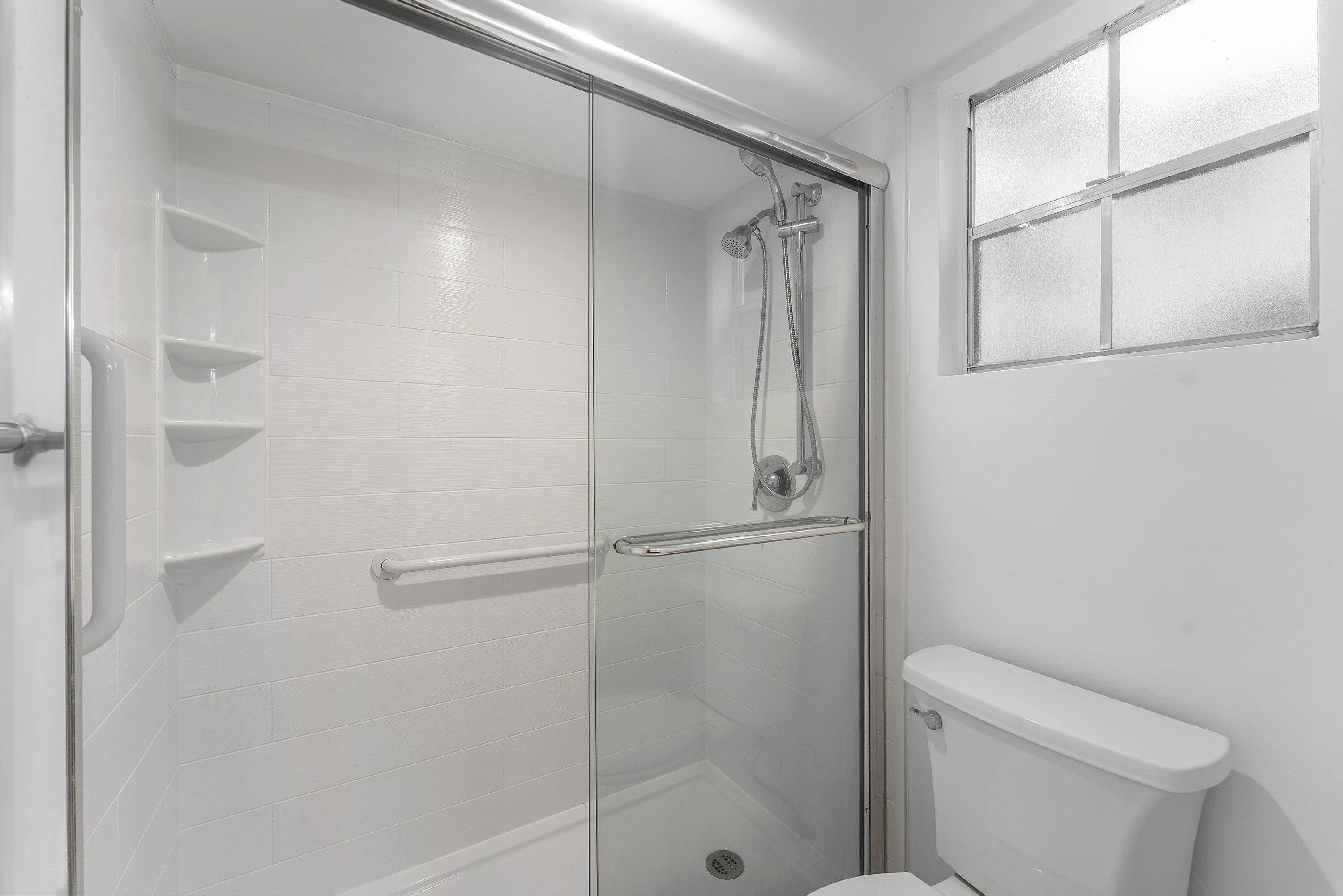 Shower enclosure with clear glass sliding doors and an adjustable shower head