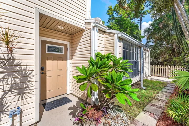 Front entrance featuring a paneled door with decorative glass insert, complemented by beige horizontal siding