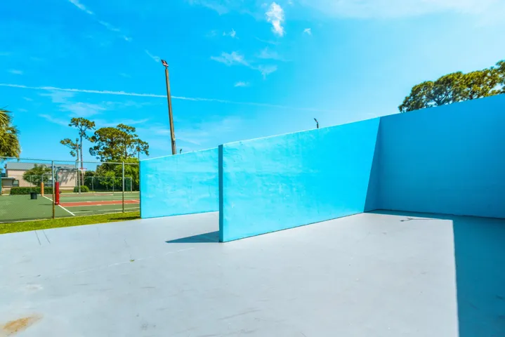 Outdoor recreational area featuring a light blue paved surface and vibrant blue walls