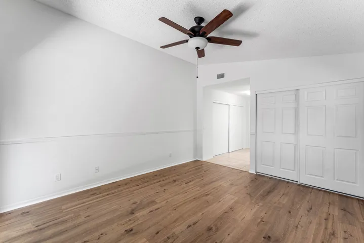 Room featuring wood-finish flooring, vaulted ceiling, and a ceiling fan with integrated lighting