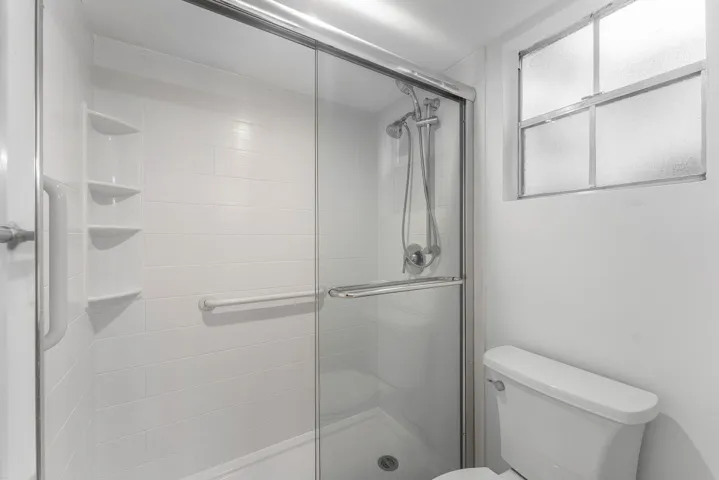 Shower enclosure with clear glass sliding doors and an adjustable shower head
