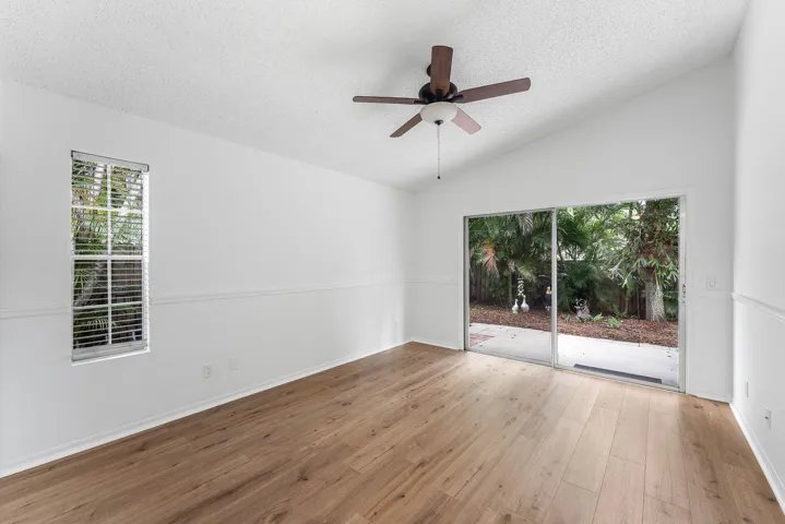 Vaulted ceiling room featuring light wood-finish flooring, a contemporary ceiling fan, and white walls with chair rail molding