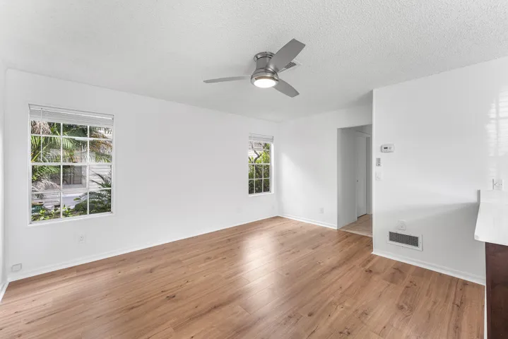 Spacious room with wood-finish flooring, white walls, and bright natural light from multiple windows