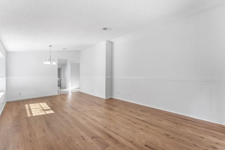 Spacious room featuring wood-finish flooring, white walls with wainscoting, and a ceiling-mounted light fixture