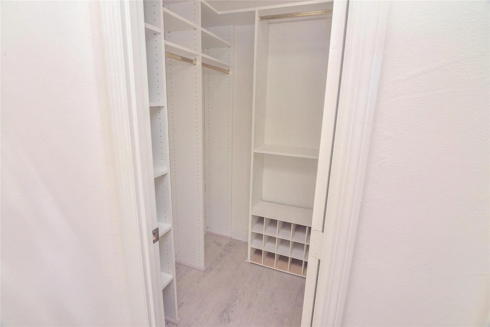 Custom white built-in closet organization system featuring shelving, hanging rods, and a shoe rack
