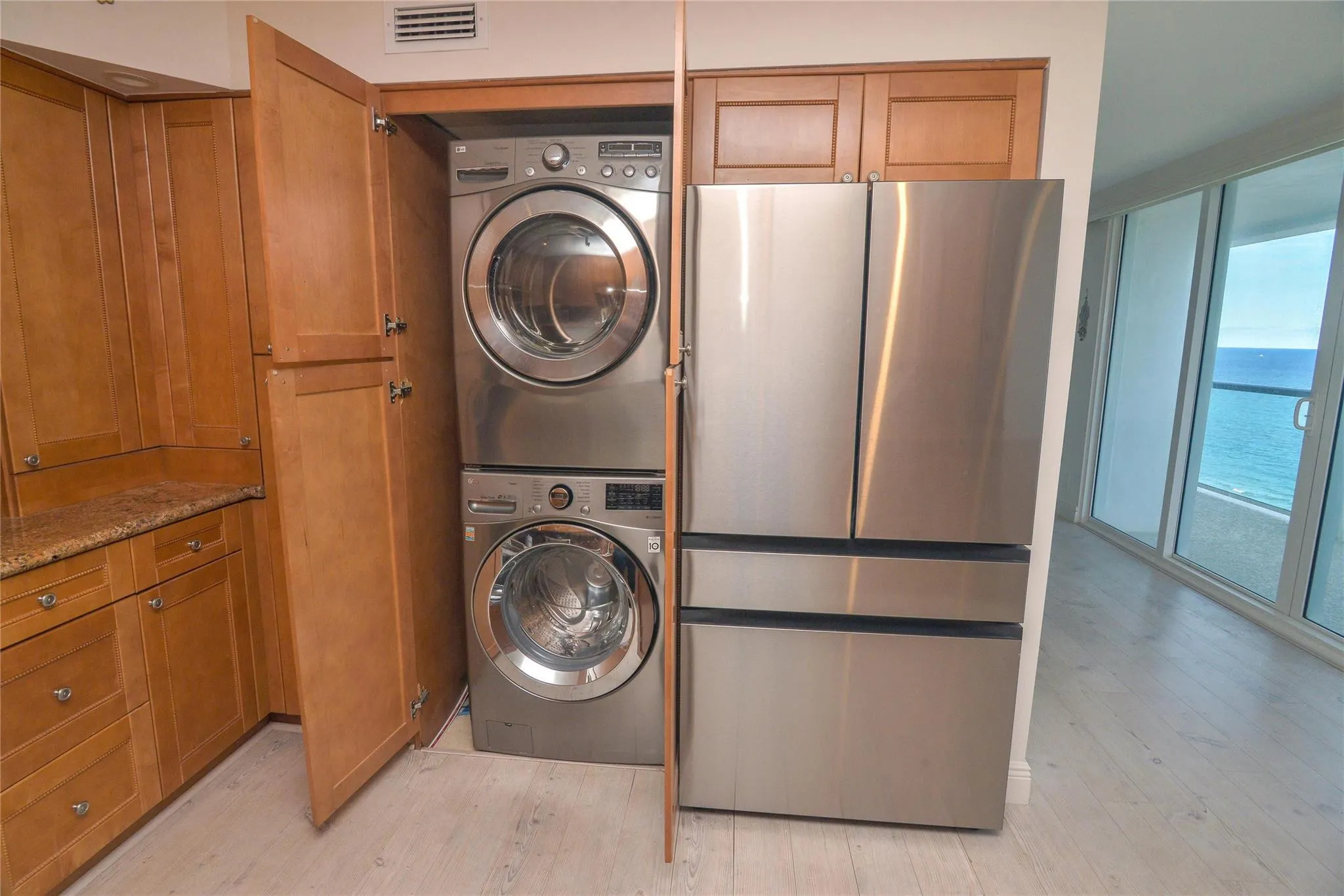 Stainless steel French door refrigerator and upgraded, barely used washer and dryer appliances within a light wood-finish cabinetry arrangement