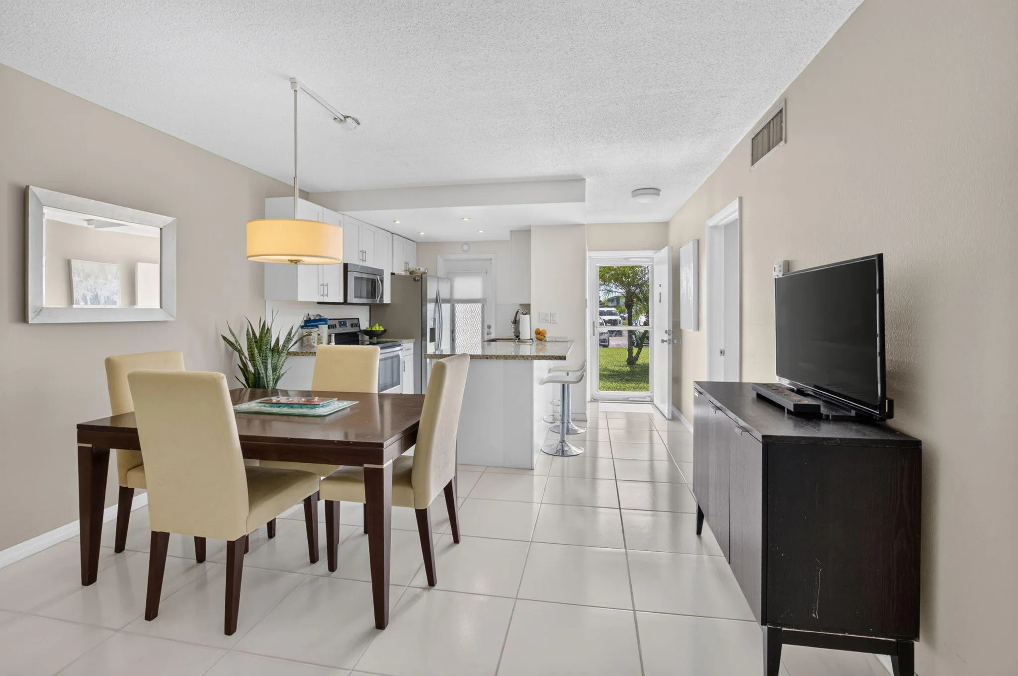 Open-concept living area featuring a kitchen with stainless steel appliances, a breakfast bar, and white cabinetry