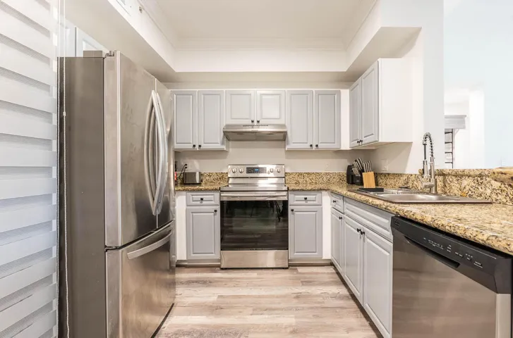 Kitchen featuring stainless steel appliances, light gray and white cabinetry, stone countertops, and wood-finish flooring