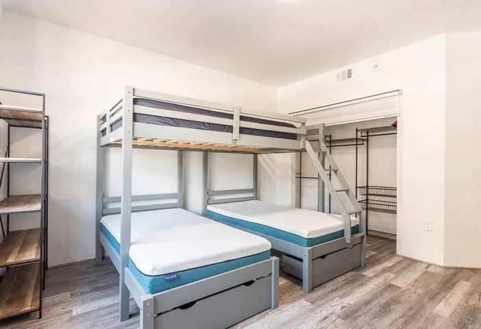 Room featuring wood-finish flooring, a built-in closet system with wire shelving, and overhead lighting