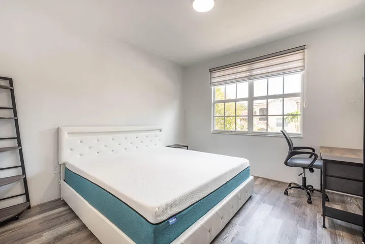 Room featuring wood-finish flooring, a large window with horizontal blinds, and a ceiling-mounted light fixture