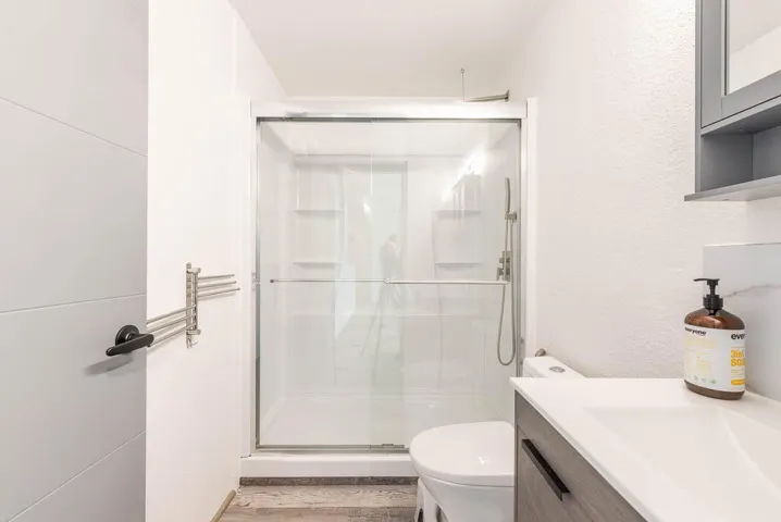 Shower enclosure with glass sliding doors, white tile surround, and built-in shelving