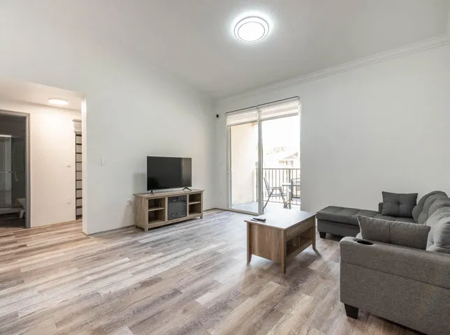 Spacious living area featuring wood-finish flooring, white walls, and a recessed ceiling light