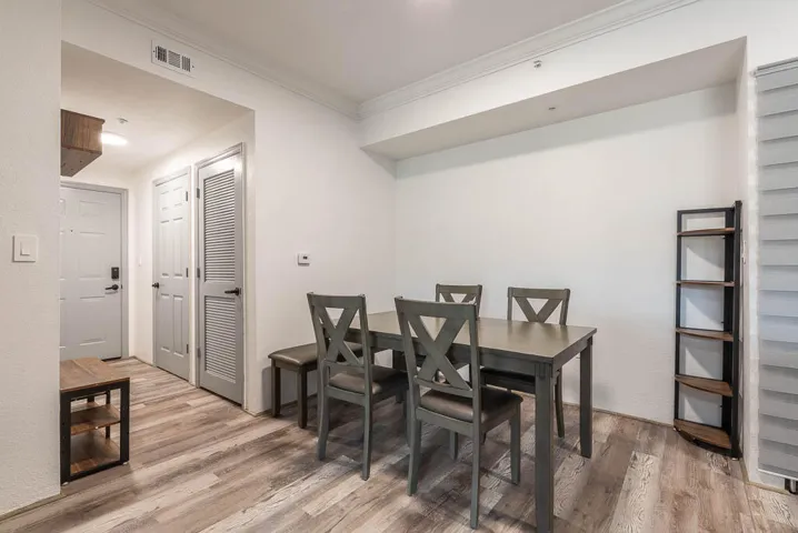 Dining area with wood-finish flooring, crown molding, and two panel doors