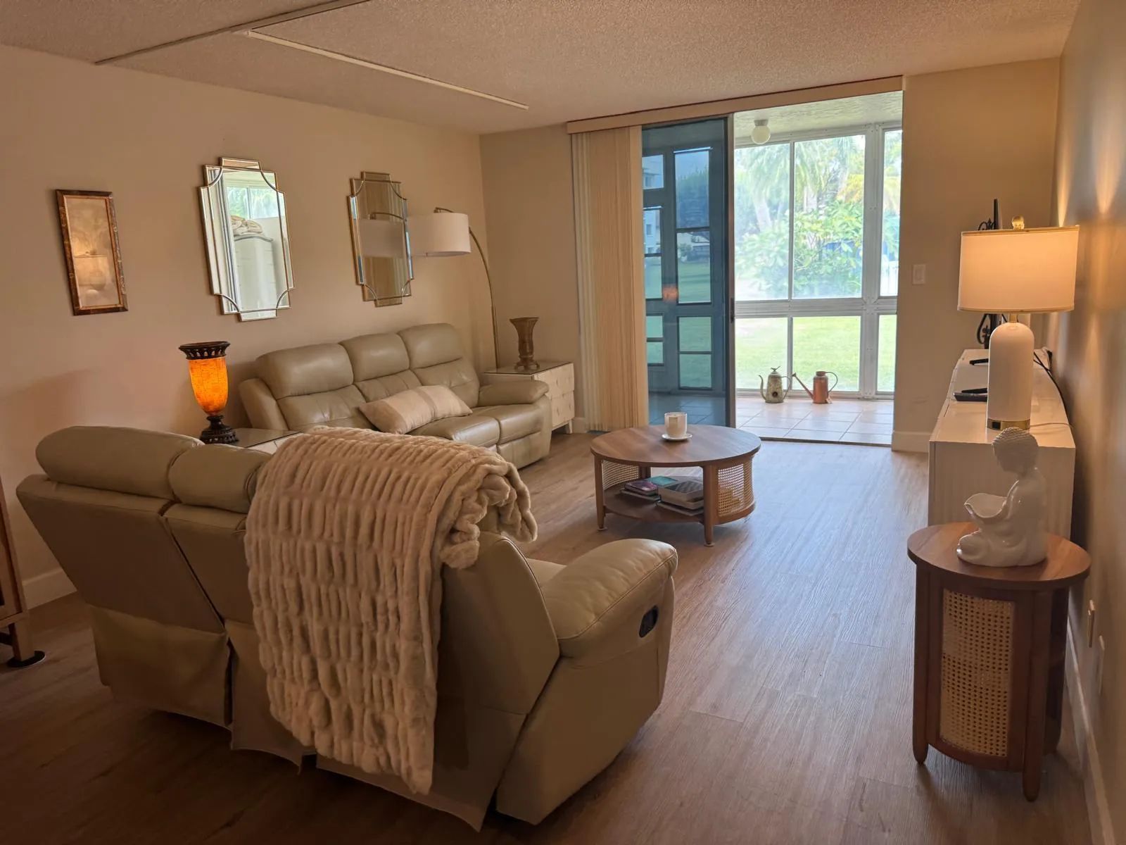Spacious living area featuring wood-finish flooring, a wall of decorative mirrors, and recessed lighting
