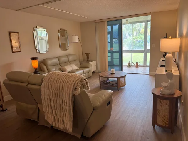 Spacious living area featuring wood-finish flooring, a wall of decorative mirrors, and recessed lighting