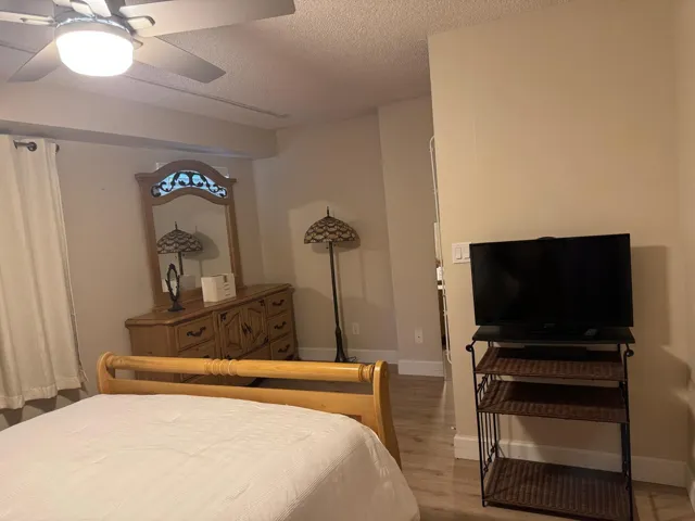 Bedroom featuring wood-finish flooring, a ceiling fan with integrated lighting, and neutral wall tones