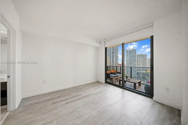 Living area featuring wood-finish flooring, floor-to-ceiling sliding glass doors, and a private balcony