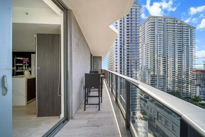 Covered balcony featuring tile flooring, glass panel railing, and sliding glass door entry