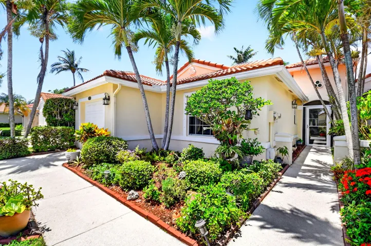 Exterior featuring a terracotta tile roof, light-toned stucco finish, and an arched entry with a glass-paneled door