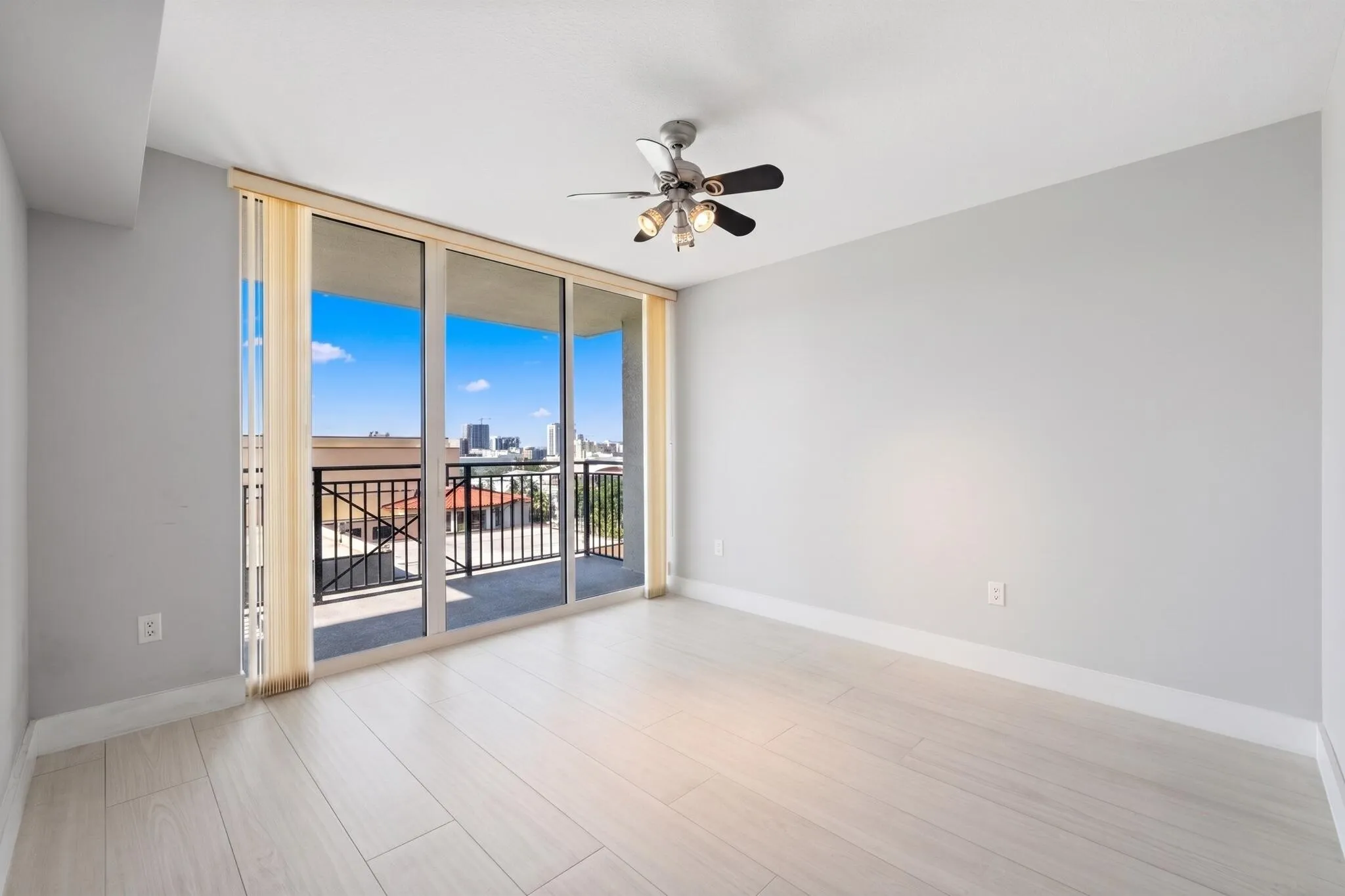 Spacious second suite with light wood-look porcelain tile flooring, ceiling fan, walk-in closet & sliding glass doors opening to its own private covered terrace.