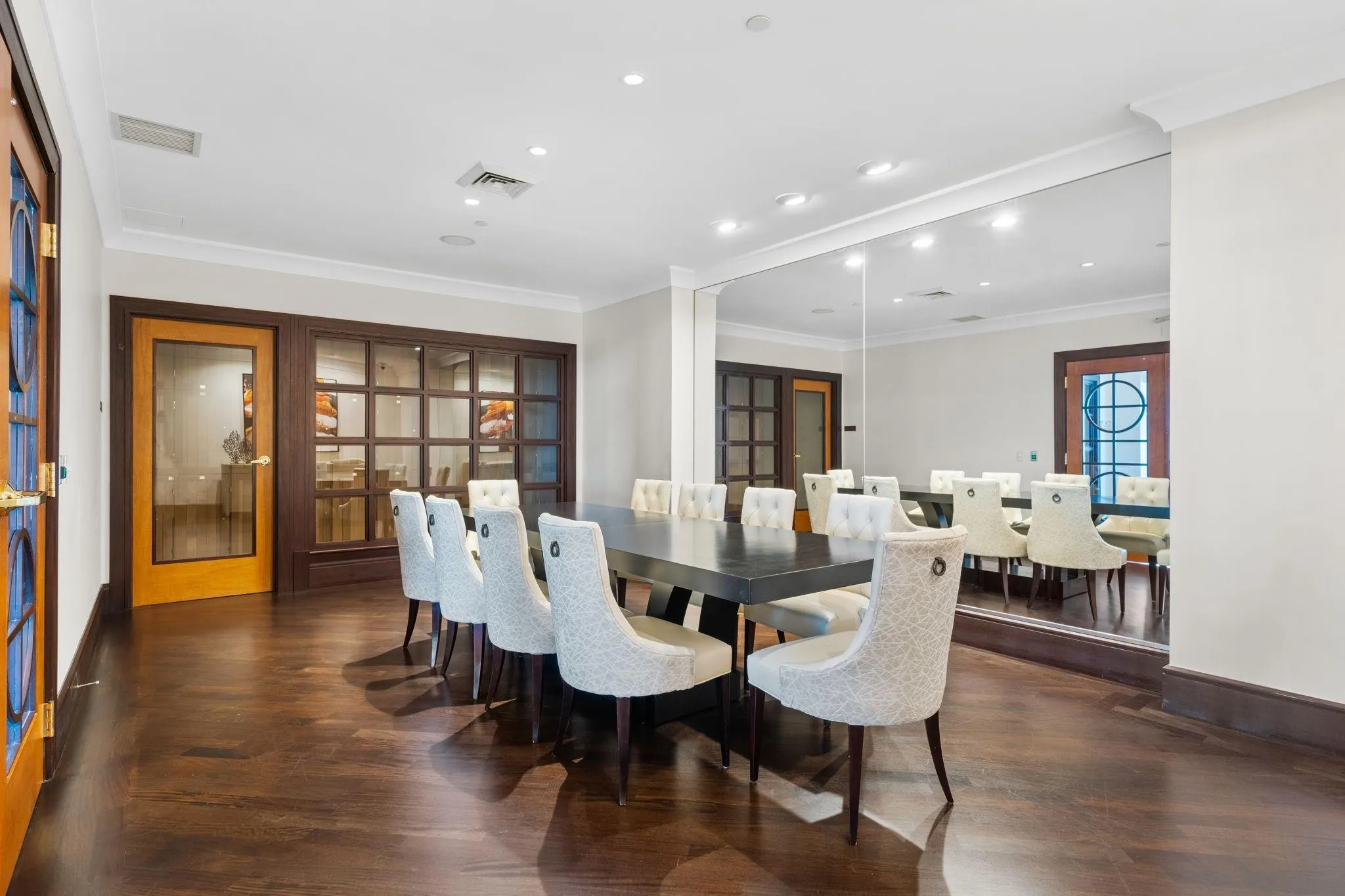 Private wine room with a communal table, refined seating & mirrored wall detailing for intimate gatherings.
