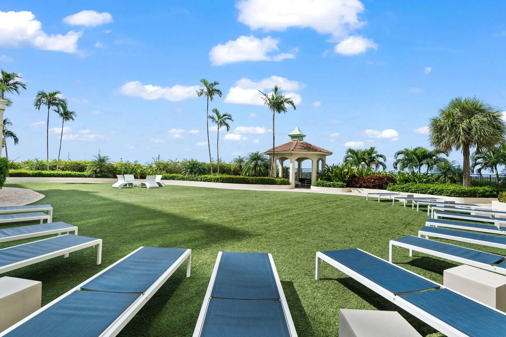 Landscaped green space with chaise lounges, walking paths & tropical landscaping near the waterfront.