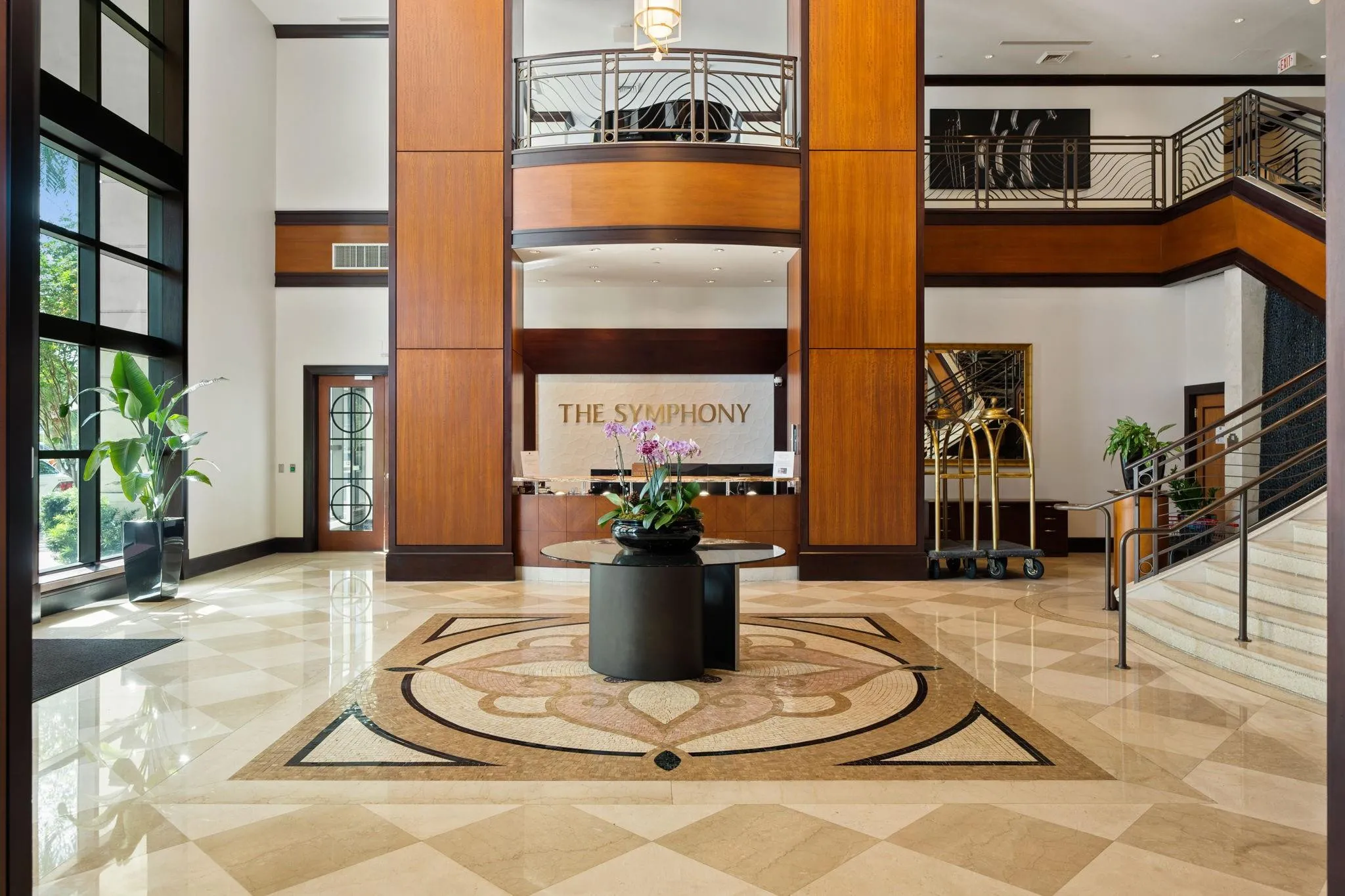 Elegant lobby featuring mosaic marble flooring, architectural wood detailing, a staffed front desk & valet service nearby.