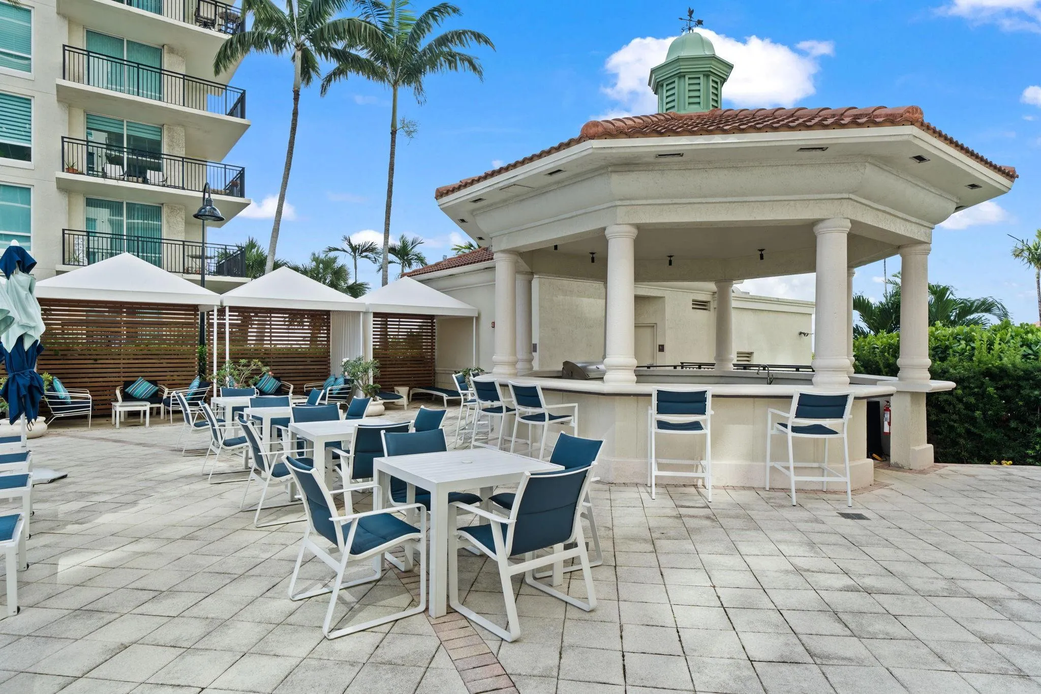 Poolside outdoor kitchen with grill, bar seating & space for waterfront dining, entertaining & relaxation.