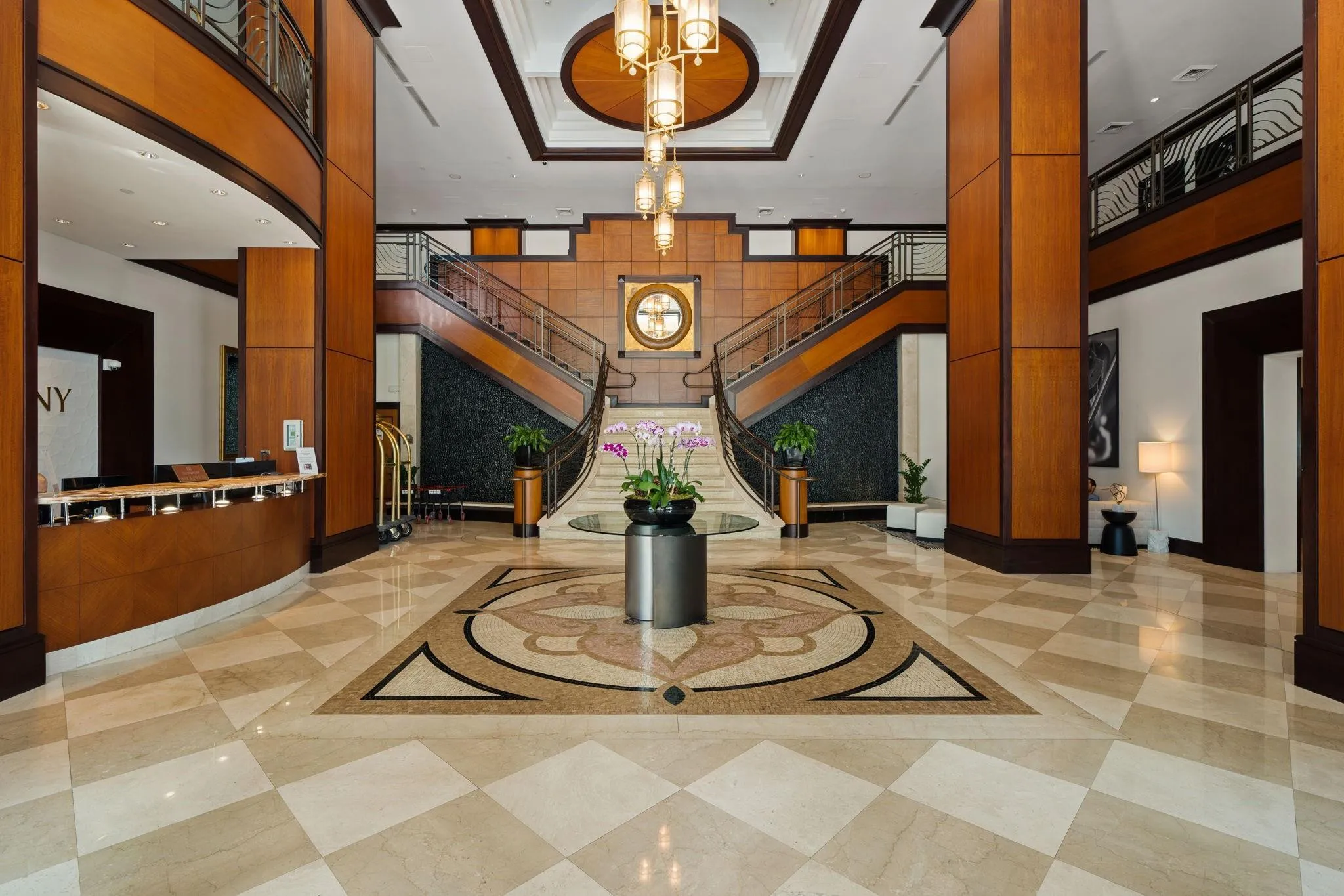 Grand two-story lobby with marble flooring, sweeping double staircases & a staffed front desk.