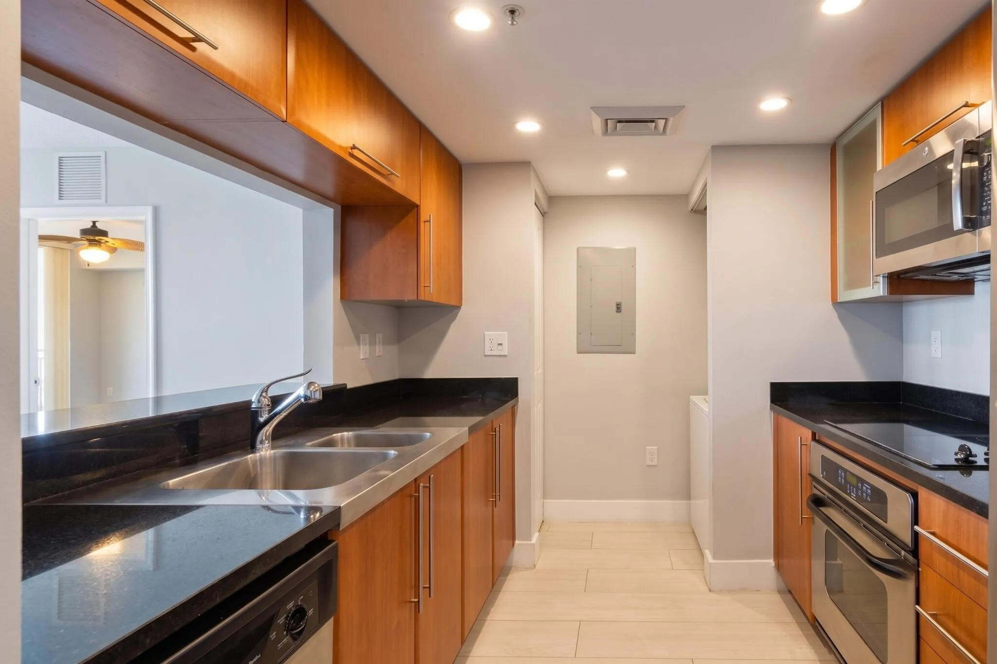 Well-appointed kitchen featuring granite countertops, warm-toned cabinetry, stainless-steel appliances & a pass-through breakfast bar.
