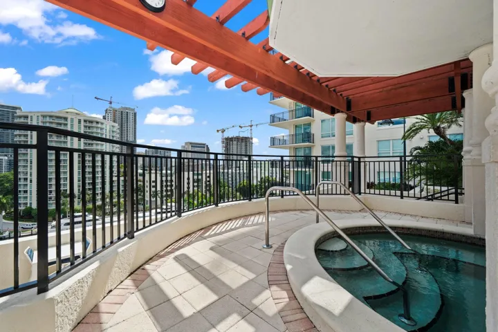 Outdoor hot tub set beneath a pergola, offering a relaxing retreat with surrounding skyline views.