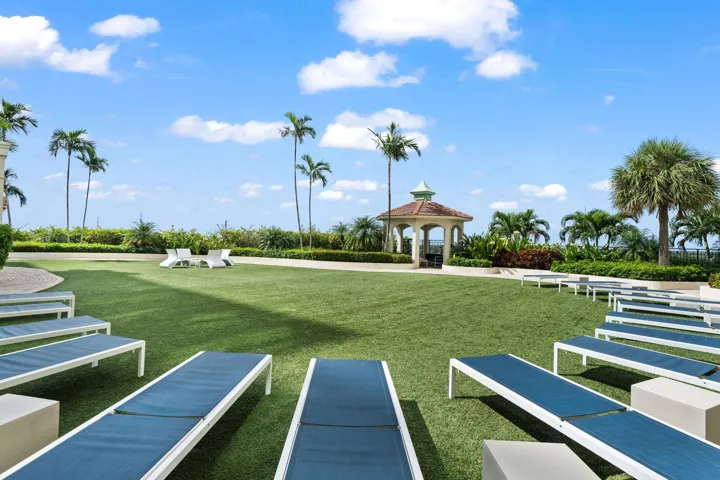 Landscaped green space with chaise lounges, walking paths & tropical landscaping near the waterfront.
