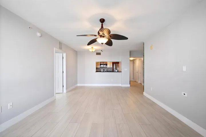 Wide view of the open living & dining areas, featuring a kitchen pass-through, ceiling fans & a natural connection between the main gathering spaces.