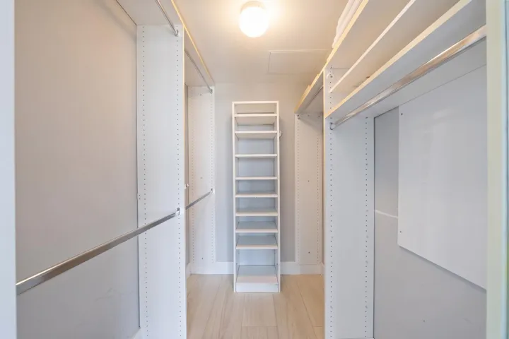 Walk-in closet with extensive custom built-ins, including shelving, drawers, hanging space & dedicated shoe storage.