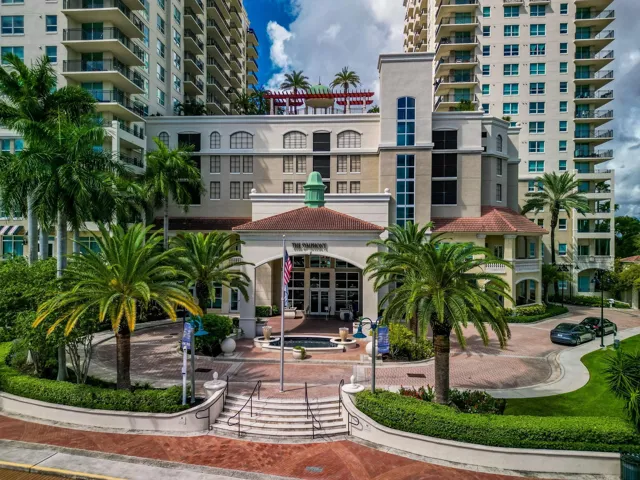 Palm-lined entrance to The Symphony, framed by landscaped grounds & an elegant riverfront setting.