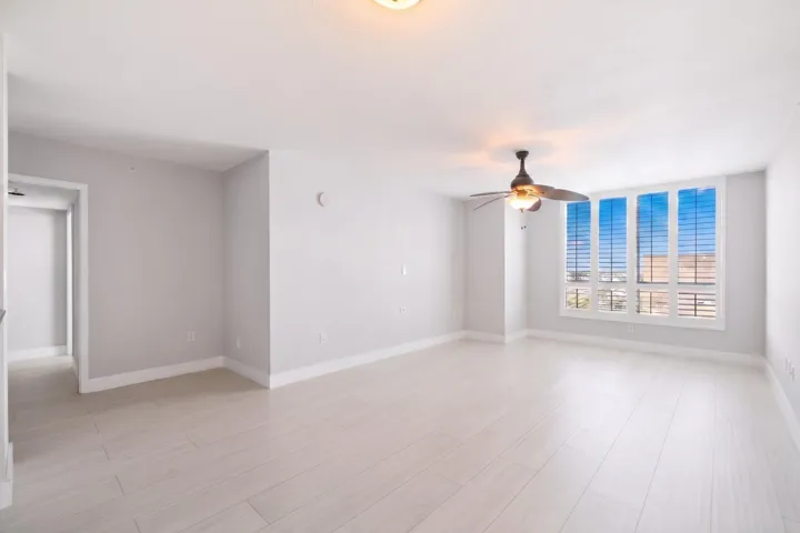 Bright, open living area with light wood-look porcelain tile flooring, large windows with plantation shutters & flexible space for relaxing or entertaining.
